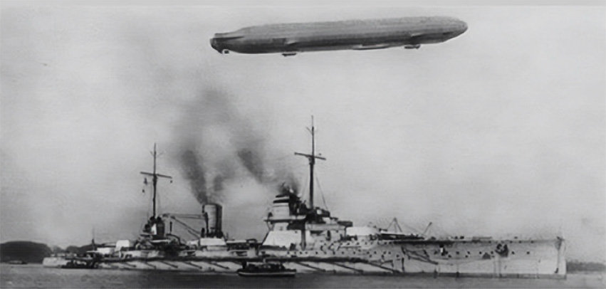 An airship flies over a battleship.